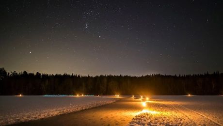 Facklor lyser upp en vintrig natt på Trehörningens is.